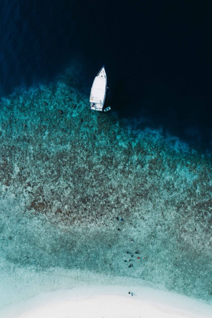Velero fondeado sobre aguas turquesas, visto desde el aire