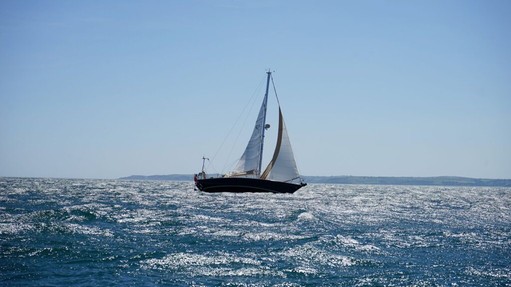 Velero navegando a vela por la costa en un día soleado
